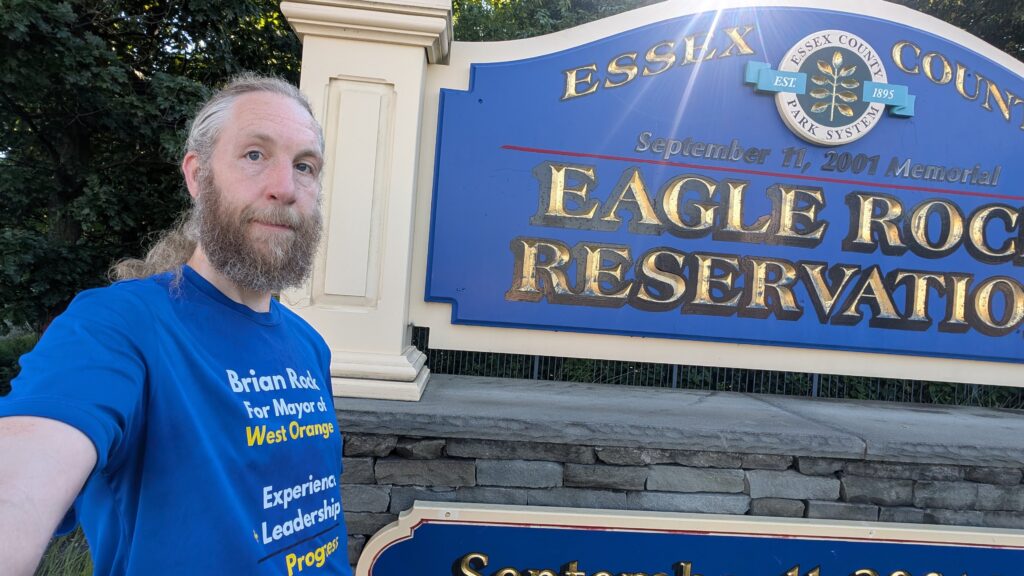 Brian Rock, candidate for West Orange Mayor, standing in front of the sign at the entrance of Eagle Rock Reservation.
