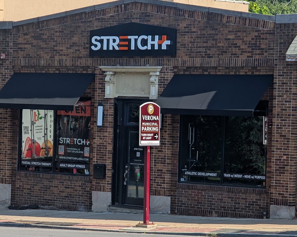 A sign in Verona pointing towards a municipal parking lot, in front of a local small business